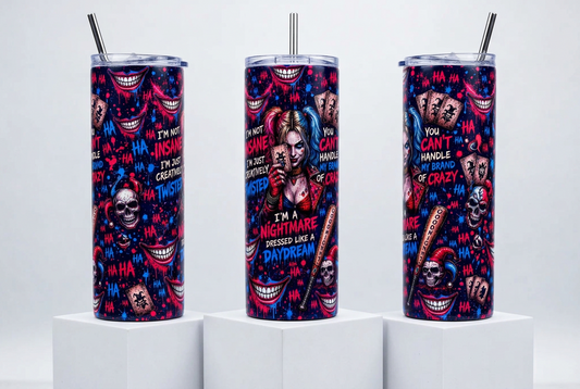 Three tall insulated tumblers with clear lids and metal straws, standing on white pedestals against a light gray studio background. The tumblers feature a vivid horror-themed print with skulls, smiling teeth, playing cards, and bold text including 'I'M A NIGHTMARE DRESSED LIKE A DAYDREAM' and 'YOU CAN'T HANDLE ME OR CRAZY'.