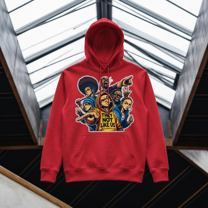 A red pullover hoodie with a colorful graphic print of cartoon characters and the text 'THEY NOT LIKE US' on the front, displayed against a modern architectural background with glass skylights.